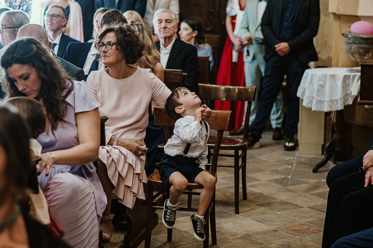 Fotografo matrimonio Torino. Matrimonio eco-consapevole a Cascina Ranverso. Cerimonia a Chieri nella chiesa dei Santi Bernardino e Rocco. Messa.Invitati , bambino guarda in alto.