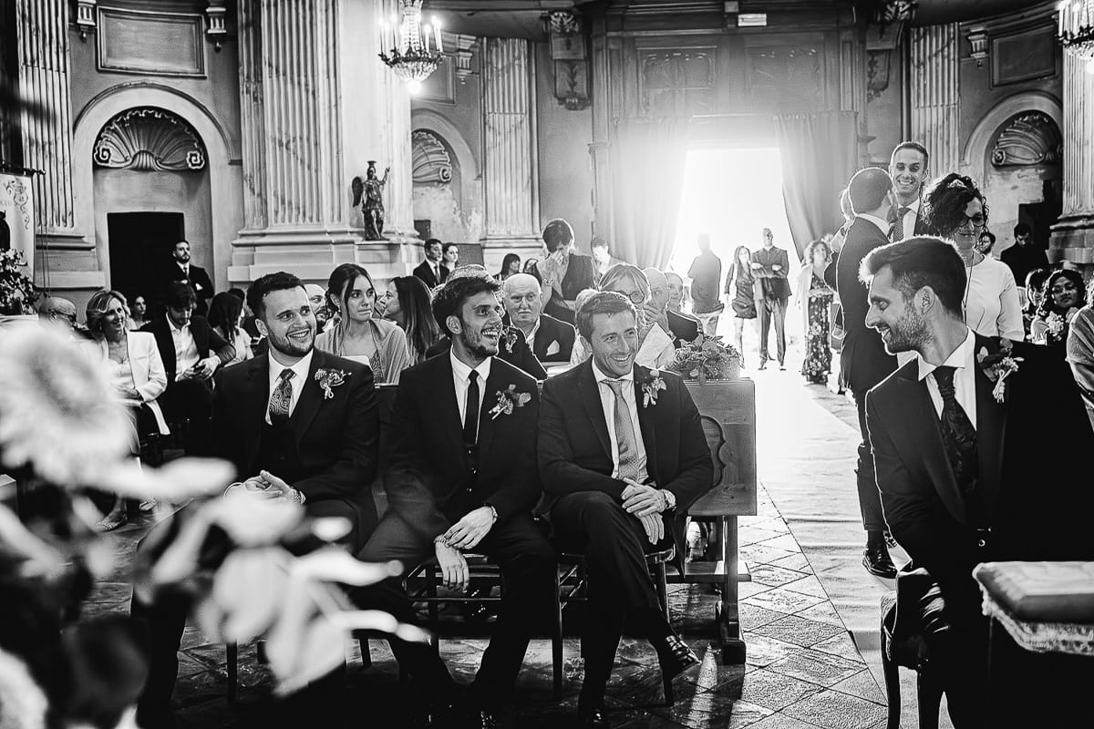 Fotografo matrimonio Torino. Matrimonio eco-consapevole a Cascina Ranverso. Cerimonia a Chieri nella chiesa dei Santi Bernardino e Rocco. Messa.Sposo guarda i testimoni