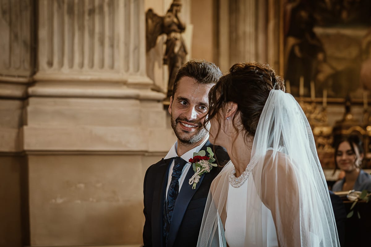 Fotografo matrimonio Torino. Matrimonio eco-consapevole a Cascina Ranverso. Cerimonia a Chieri nella chiesa dei Santi Bernardino e Rocco. Messa.Sposo guarda la sposa
