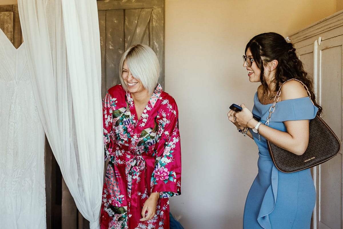 Matrimonio boho-chic da favola nel Monferrato. Matrimonio a Molare. Agriturismo "A Modo Mio". Preparazione della sposa. Sposa ride con la sua testimone.