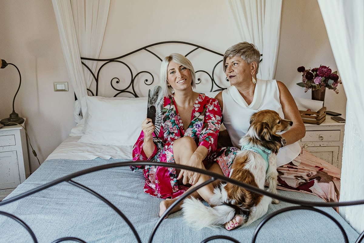 Matrimonio boho-chic da favola nel Monferrato. Matrimonio a Molare. Agriturismo "A Modo Mio". Preparazione della sposa.Sposa sul letto con la mamma e i volpini.