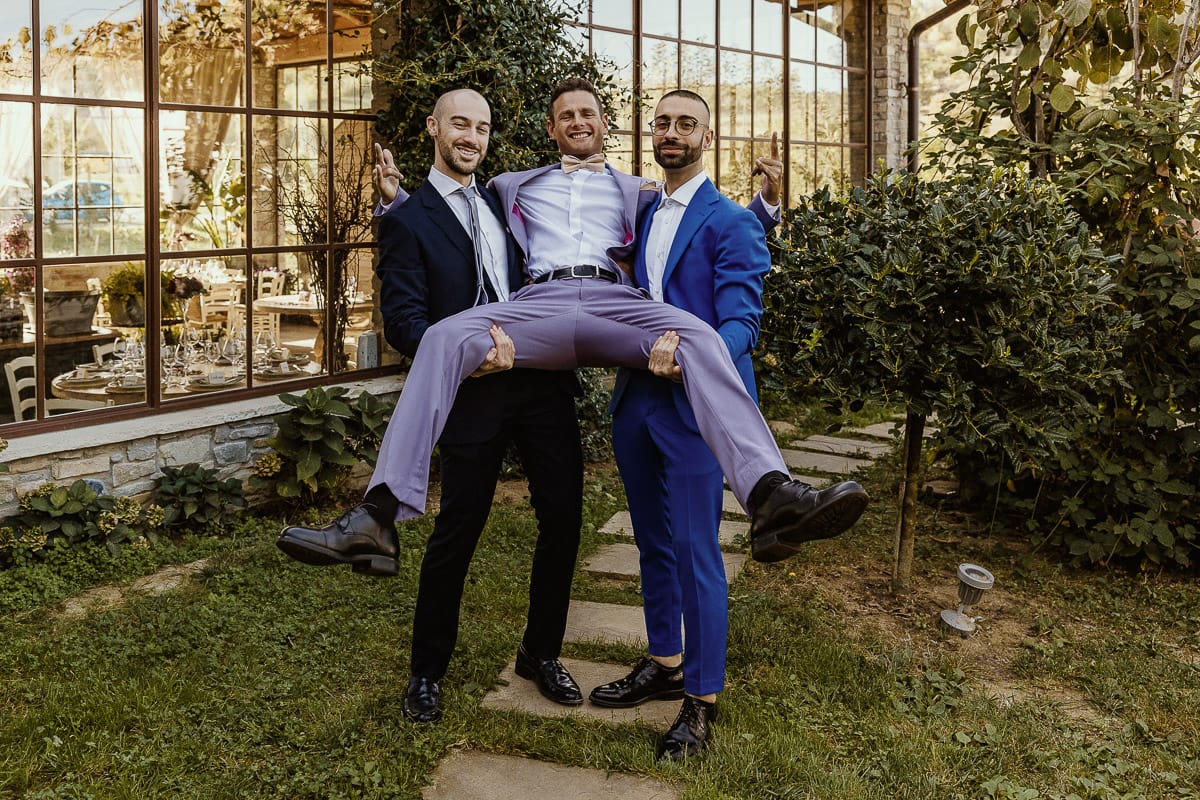 Matrimonio boho-chic da favola nel Monferrato. Matrimonio a Molare. Agriturismo "A Modo Mio". Preparazione dello sposo. Ritratto dello sposo in giardino. I testimoni lo sollevano