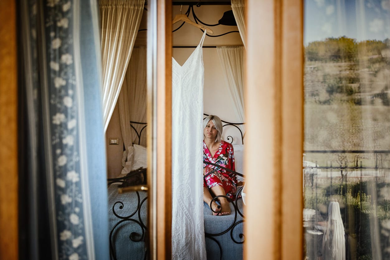 Matrimonio boho-chic da favola nel Monferrato. Matrimonio a Molare. Agriturismo "A Modo Mio". Preparazione della sposa. Sposa seduta sul letto. Ripresa dal balcone.
