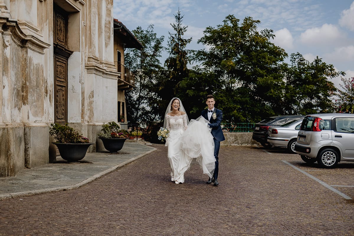 Fotografo matrimonio Torino | Tenuta La Michelina | Pinerolo. Ritratto di coppia degli sposi. Sposi camminano. lo sposo tiene l'abito della sposa.