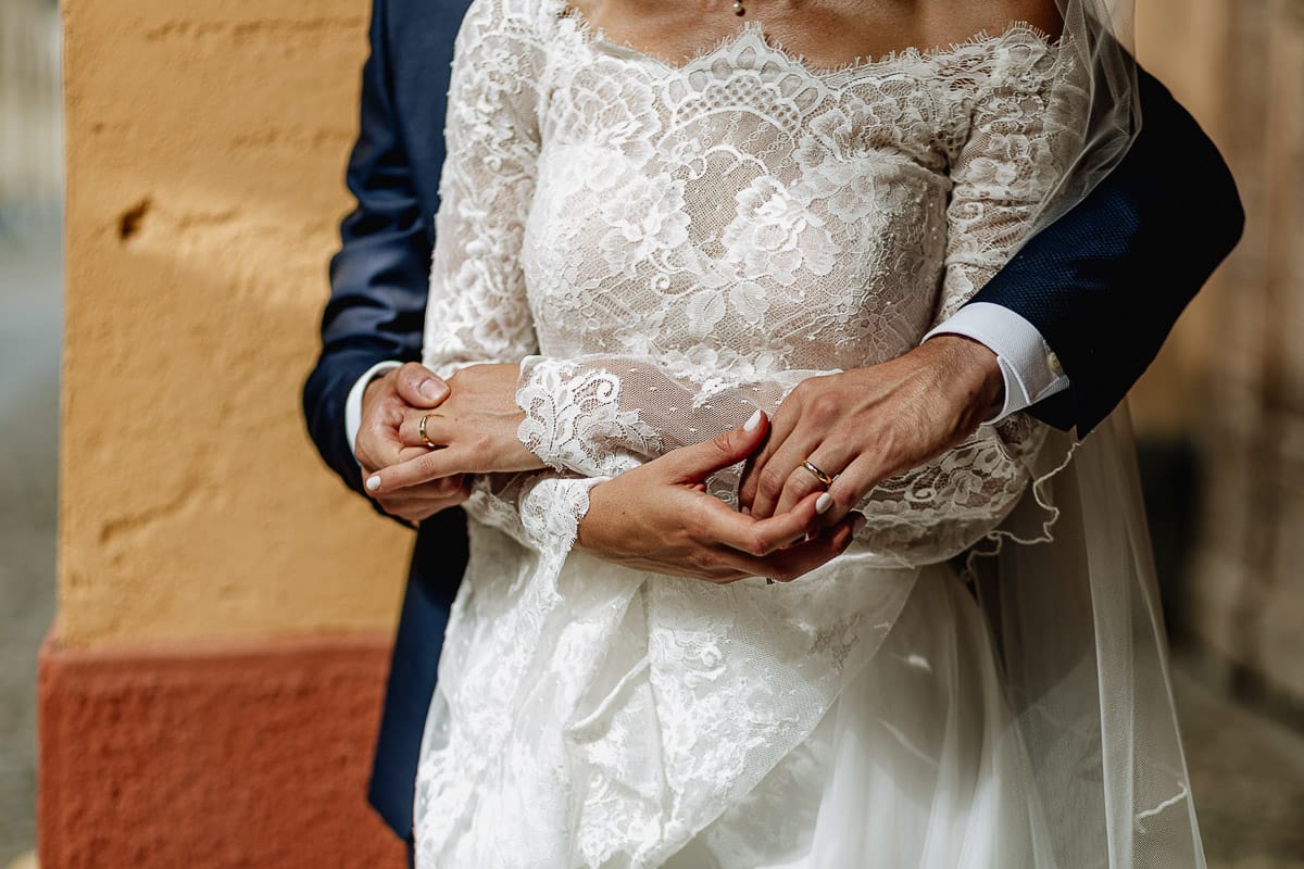Fotografo matrimonio Torino | Tenuta La Michelina | Pinerolo. Ritratto di coppia degli sposi. Sposi sotto un portico medievale. Dettaglio delle mani con gli anelli.