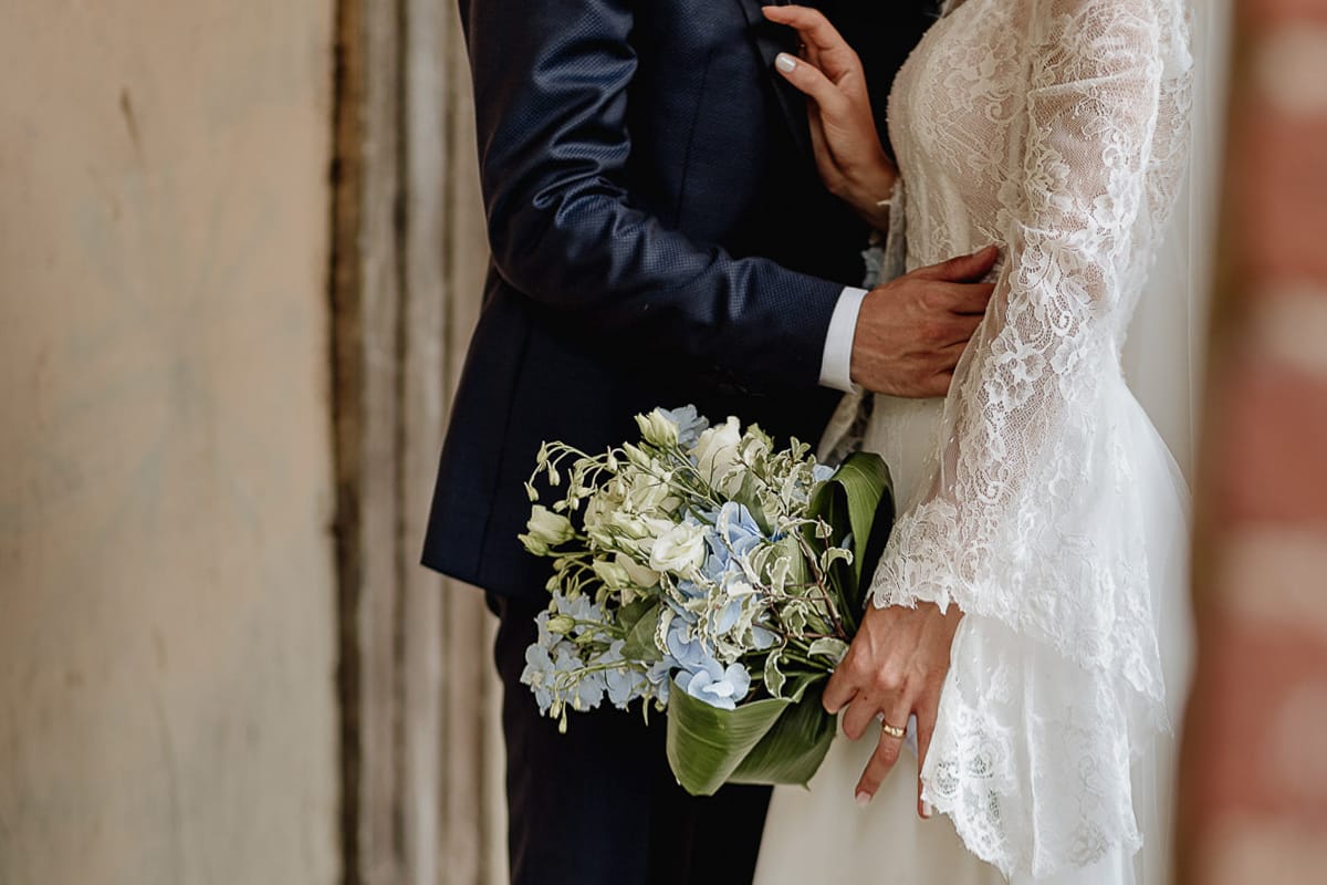 Fotografo matrimonio Torino | Tenuta La Michelina | Pinerolo. Ritratto di coppia degli sposi. Sposi sotto un portico medievale di poirino dettaglio sul bouquet