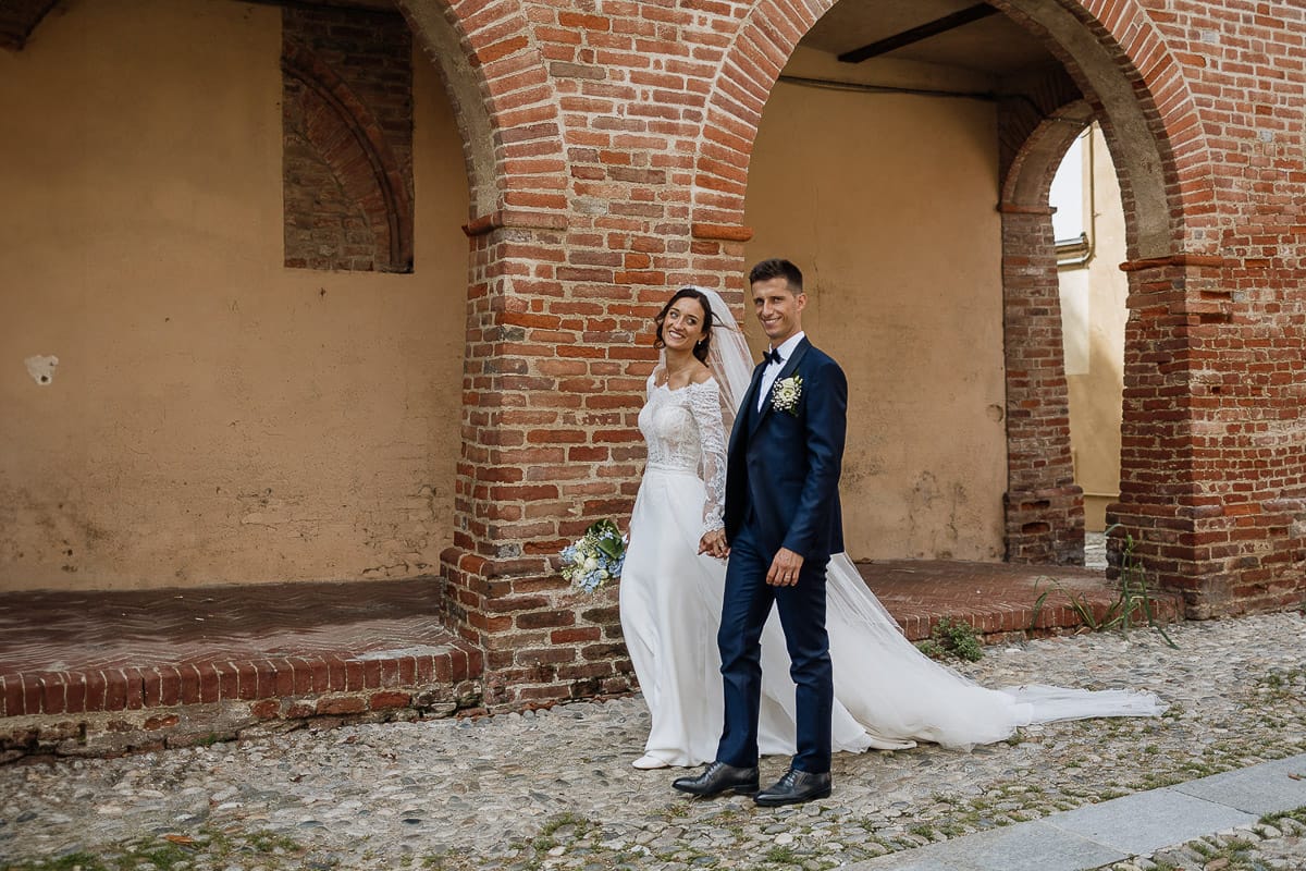 Fotografo matrimonio Torino | Tenuta La Michelina | Pinerolo. Ritratto di coppia degli sposi. Sposi sotto nel centro storico di Poirino. Sposi passeggiano davanti ai portici medievali.