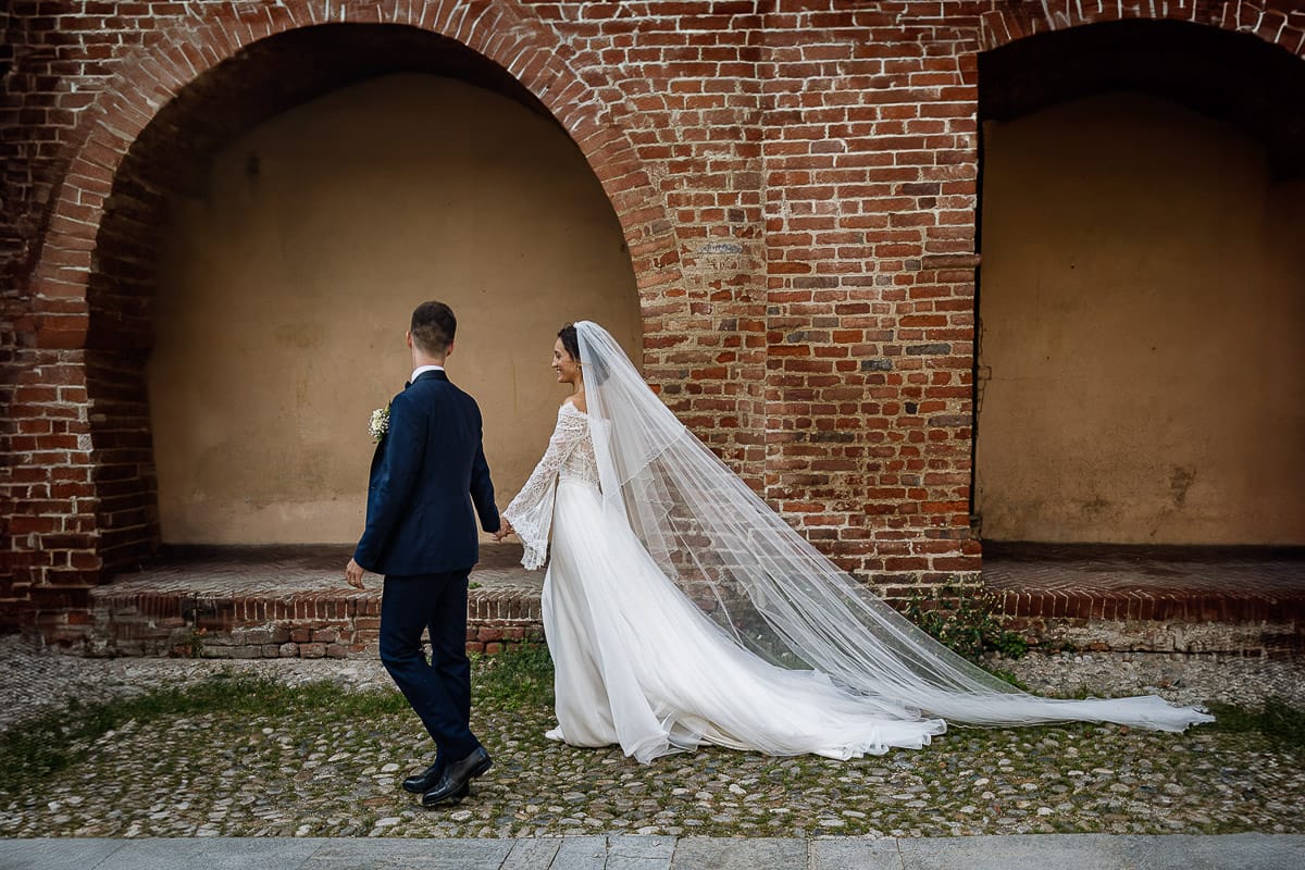 Fotografo matrimonio Torino | Tenuta La Michelina | Pinerolo. Ritratto di coppia degli sposi. Sposi sotto nel centro storico di Poirino. Sposi passeggiano davanti ai portici medievali.