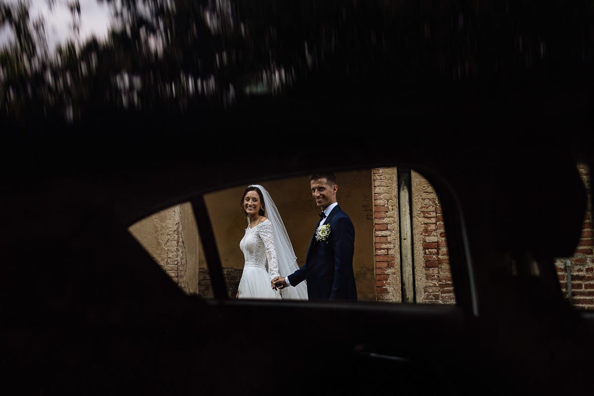 Fotografo matrimonio Torino | Tenuta La Michelina | Pinerolo. Ritratto di coppia degli sposi. Sposi sotto nel centro storico di Poirino. Sposi passeggiano davanti ai portici medievali. Ripresi dal finestrino di un'auto