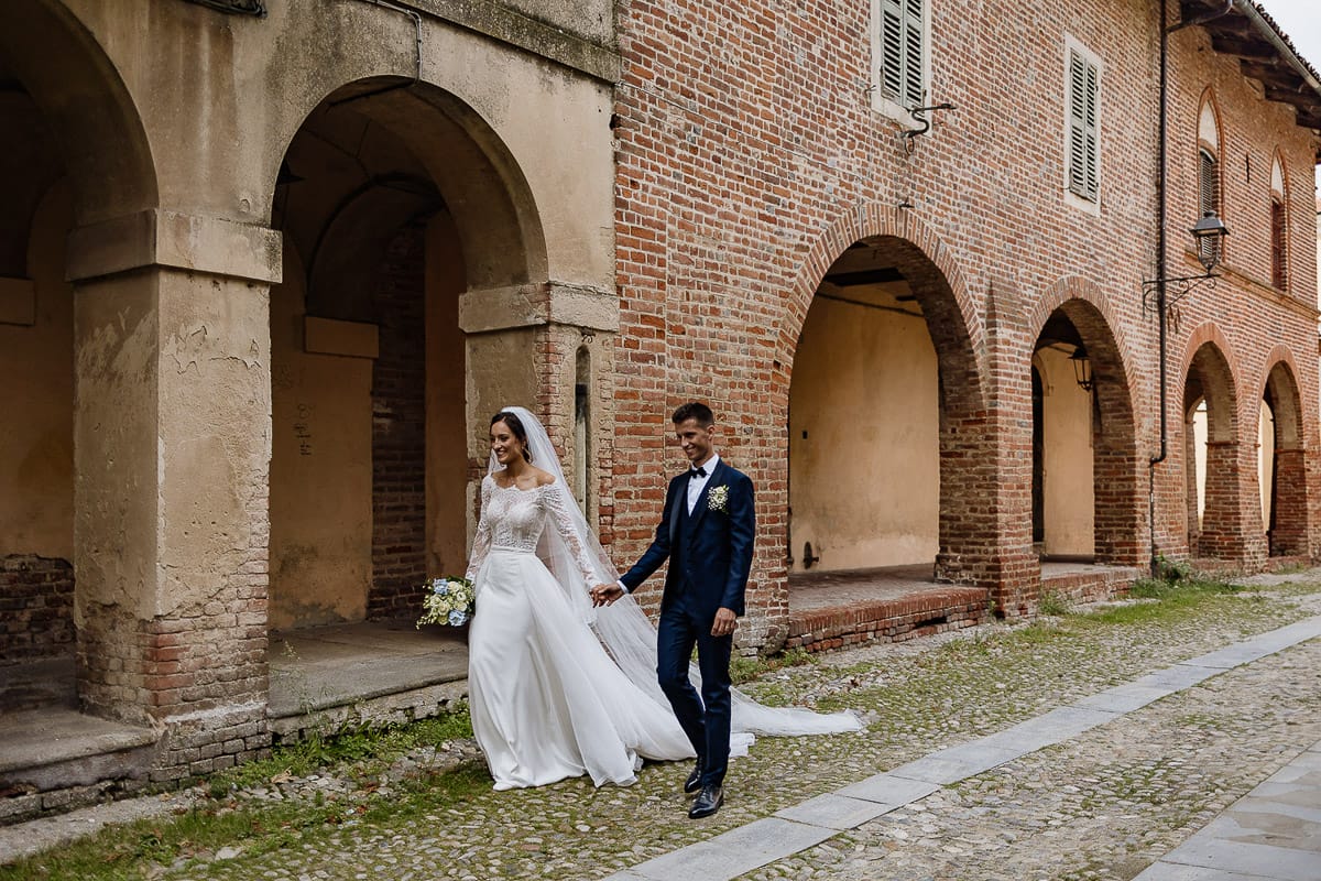 Fotografo matrimonio Torino | Tenuta La Michelina | Pinerolo. Ritratto di coppia degli sposi. Sposi sotto nel centro storico di Poirino. Sposi passeggiano davanti ai portici medievali.