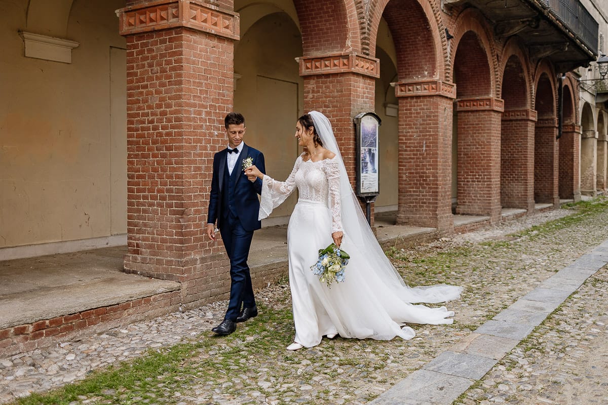 Fotografo matrimonio Torino | Tenuta La Michelina | Pinerolo. Ritratto di coppia degli sposi. Sposi sotto nel centro storico di Poirino. Sposi passeggiano davanti ai portici medievali.