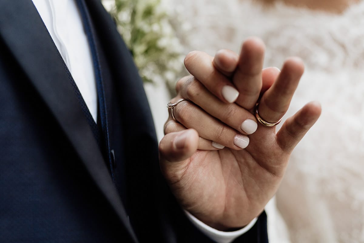 Fotografo matrimonio Torino | Tenuta La Michelina | Pinerolo. Ritratto di coppia degli sposi. Sposi sotto nel centro storico di Poirino. Sposi passeggiano davanti ai portici medievali. Dettaglio sulle mani.