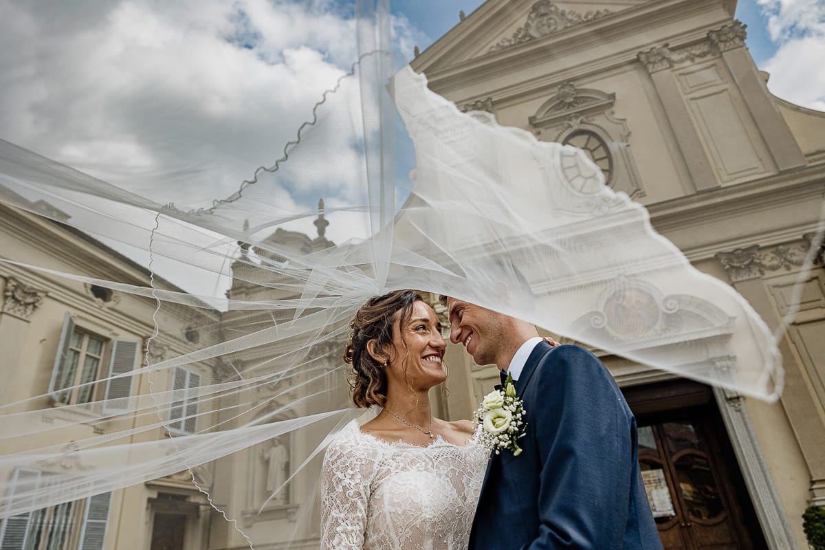 Fotografo matrimonio Torino | Tenuta La Michelina | Pinerolo. Ritratto di coppia degli sposi. Sposi sotto nel centro storico di Poirino. Sposisotto il velo davanti alla chiesa di santa Maria maggiore.