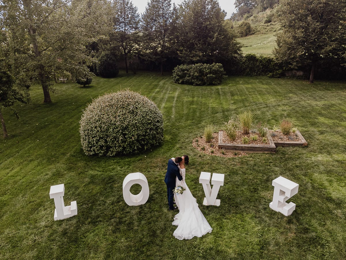 Fotografo matrimonio Torino | Tenuta La Michelina | Pinerolo. Sessione di coppia degli sposi. Sposi si baciano davanti alla scritta LOVE. Foto aerea dal drone.