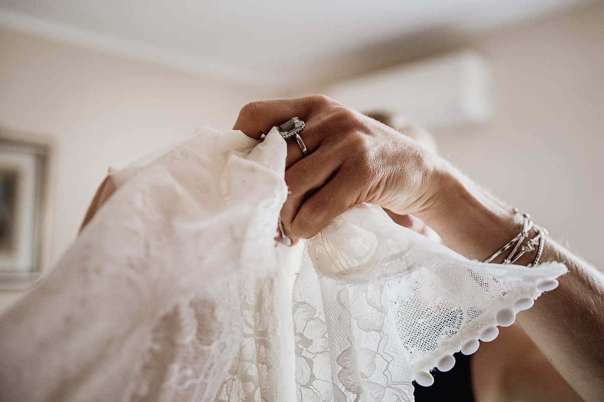 Fotografo matrimonio Torino | Tenuta La Michelina | Pinerolo. Preparazione della sposa. mano della mamma che tiene l'abito da sposa