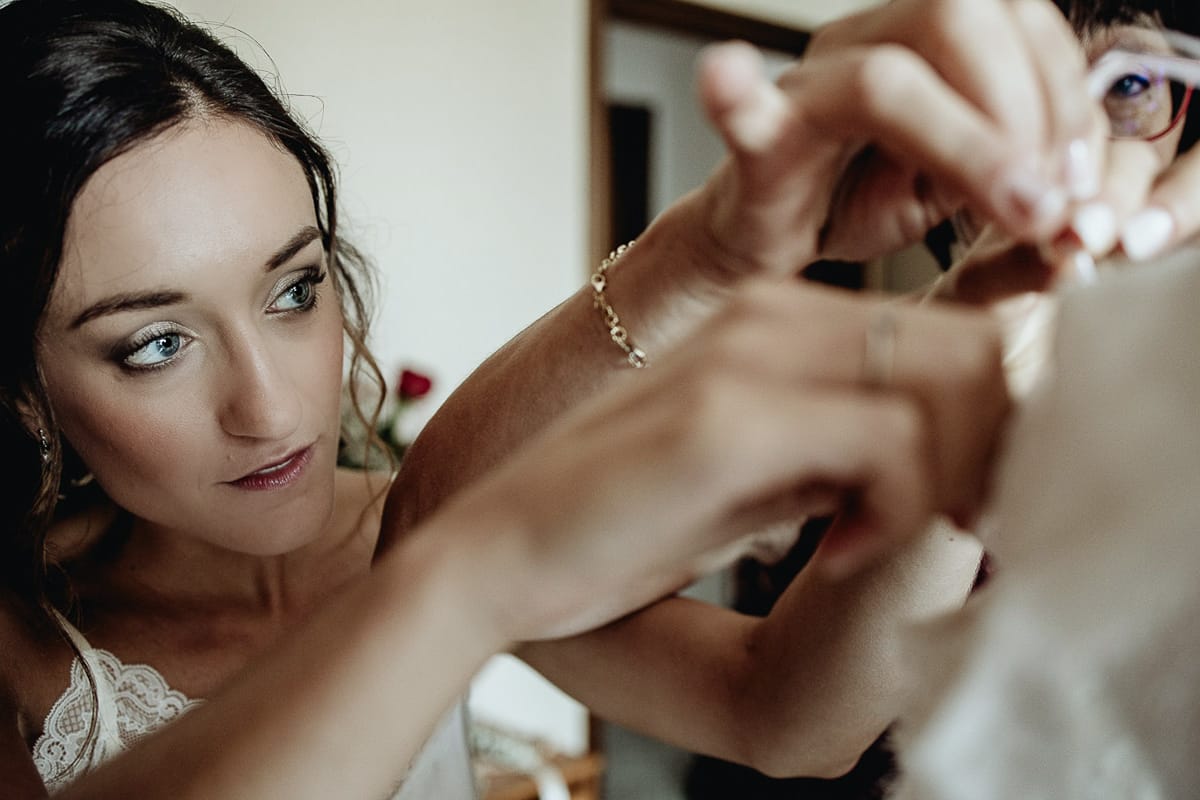 Fotografo matrimonio Torino | Tenuta La Michelina | Pinerolo. Preparazione della sposa. Sposa che guarda come viene sistemato l'abito per la vestizione