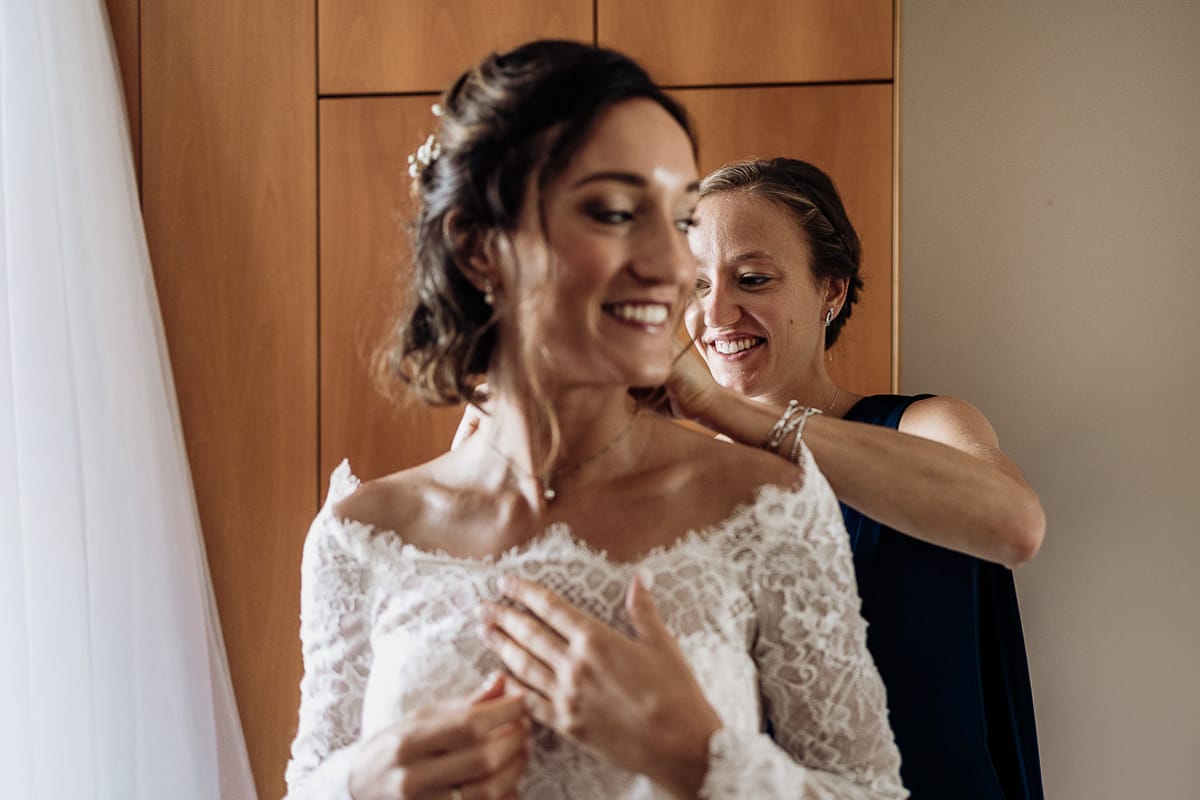 Fotografo matrimonio Torino | Tenuta La Michelina | Pinerolo. Preparazione della sposa. Vestizione della sposa . Sorella le mette il girocollo.