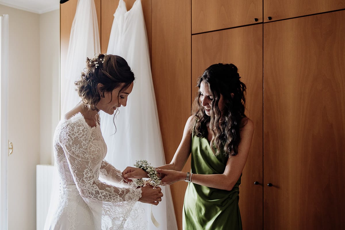 Fotografo matrimonio Torino | Tenuta La Michelina | Pinerolo. Preparazione della sposa. Vestizione della sposa . Sposa mette il corsage ad una testimone.