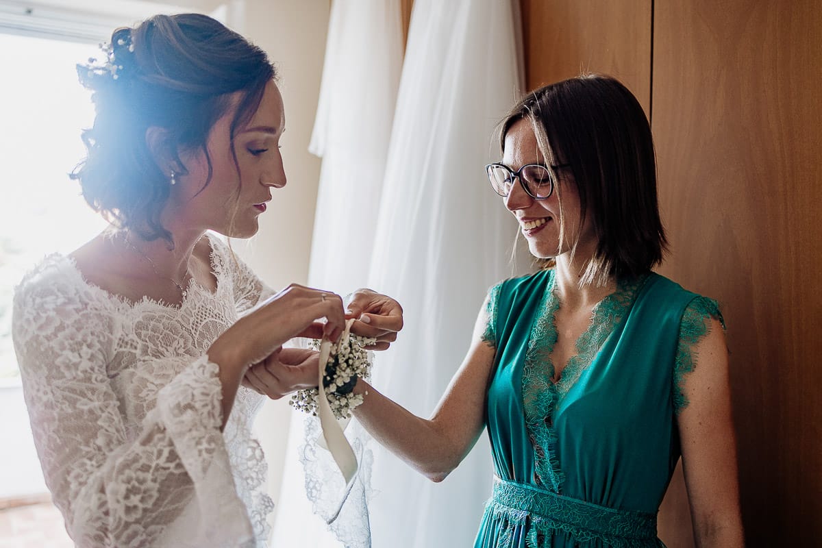 Fotografo matrimonio Torino | Tenuta La Michelina | Pinerolo. Preparazione della sposa. Vestizione della sposa . Sposa mette il corsage ad una testimone.