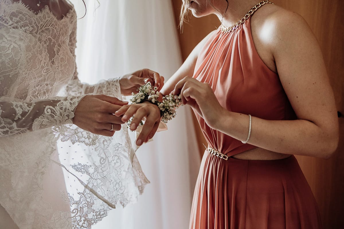 Fotografo matrimonio Torino | Tenuta La Michelina | Pinerolo. Preparazione della sposa. Vestizione della sposa . Sposa mette il corsage ad una testimone.