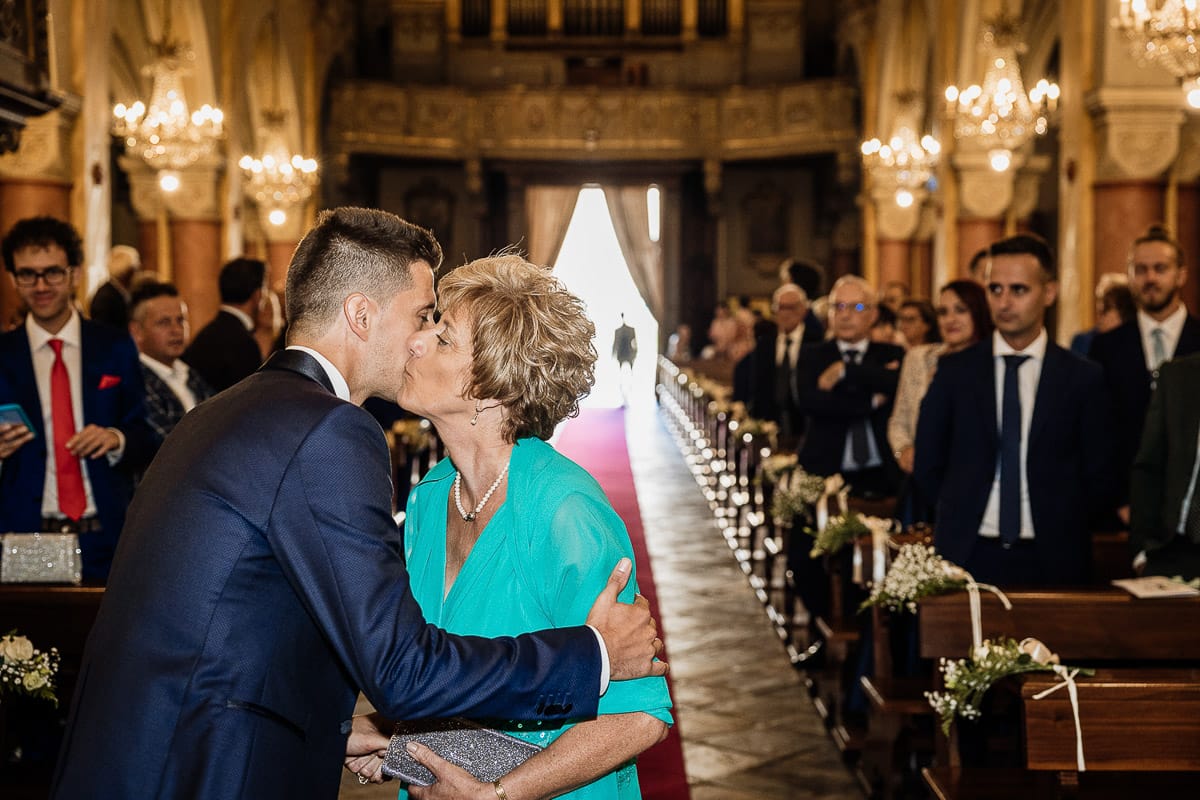 Fotografo matrimonio Torino | Tenuta La Michelina | Pinerolo. Cerimonia religiosa nella chiesa di Santa Maria Maggiore di Poirino. Sposo bacia la mamma.
