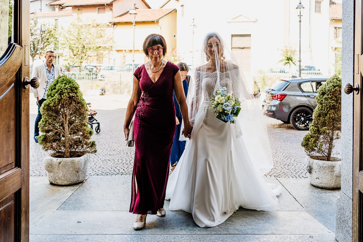 Fotografo matrimonio Torino | Tenuta La Michelina | Pinerolo. Cerimonia religiosa nella chiesa di Santa Maria Maggiore di Poirino. Ritratto della sposa che entra in chiesa con la mamma