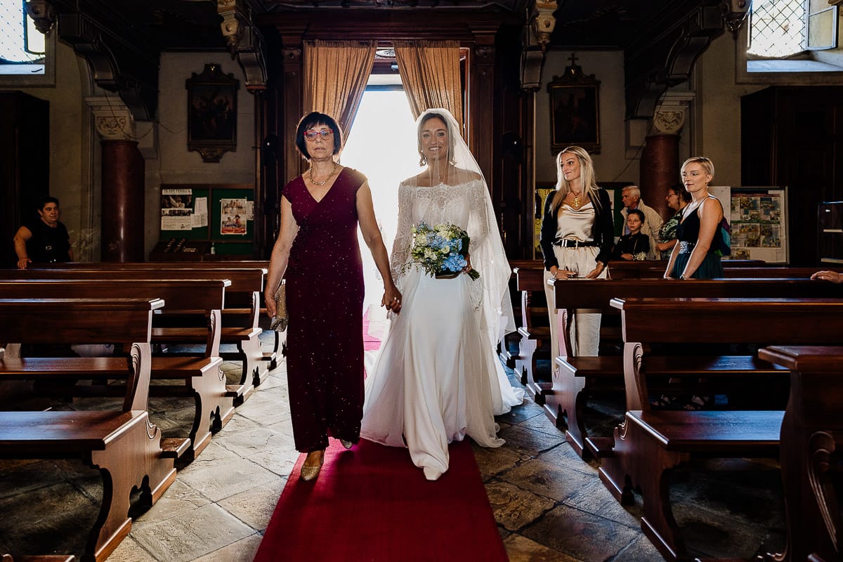 Fotografo matrimonio Torino | Tenuta La Michelina | Pinerolo. Cerimonia religiosa nella chiesa di Santa Maria Maggiore di Poirino. Ritratto della sposa che percorre la navata con la mamma.