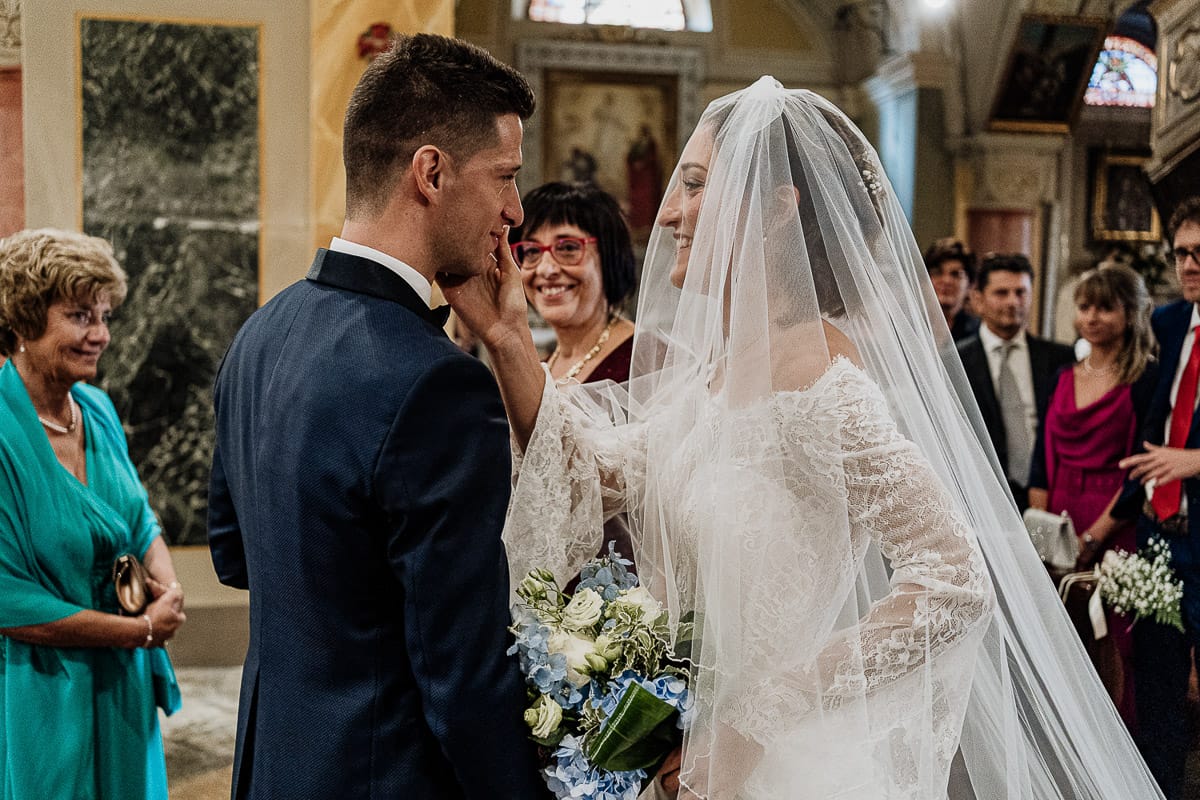Fotografo matrimonio Torino | Tenuta La Michelina | Pinerolo. Cerimonia religiosa nella chiesa di Santa Maria Maggiore di Poirino. Sposa accarezza lo sposo.
