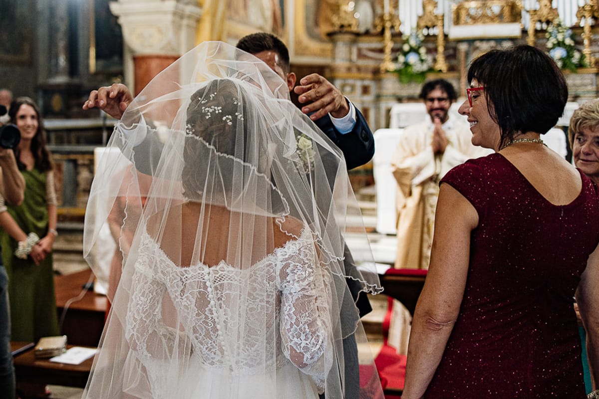 Fotografo matrimonio Torino | Tenuta La Michelina | Pinerolo. Cerimonia religiosa nella chiesa di Santa Maria Maggiore di Poirino. Sposo toglie il velo dal viso della sposa.