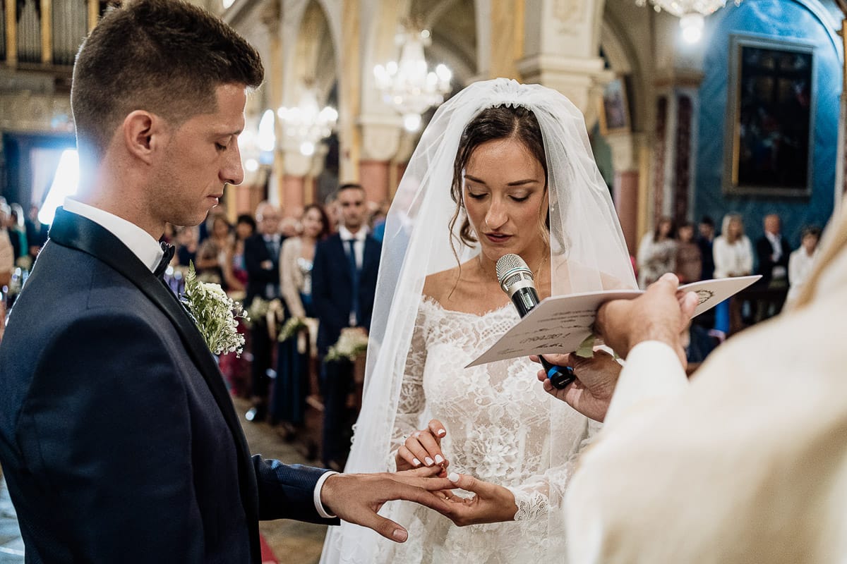 Fotografo matrimonio Torino | Tenuta La Michelina | Pinerolo. Cerimonia religiosa nella chiesa di Santa Maria Maggiore di Poirino. Sposa mette l'anello allo sposo.