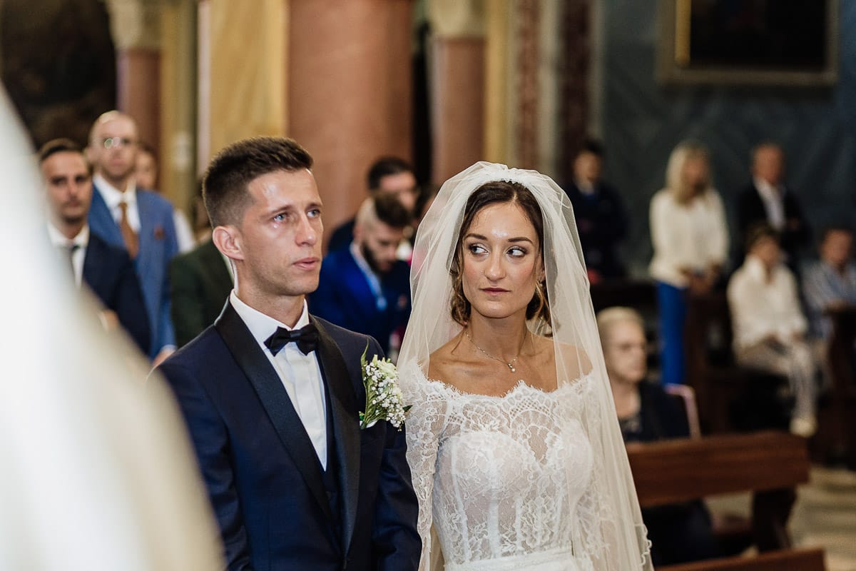 Fotografo matrimonio Torino | Tenuta La Michelina | Pinerolo. Cerimonia religiosa nella chiesa di Santa Maria Maggiore di Poirino. Sposo piange sposa lo guarda