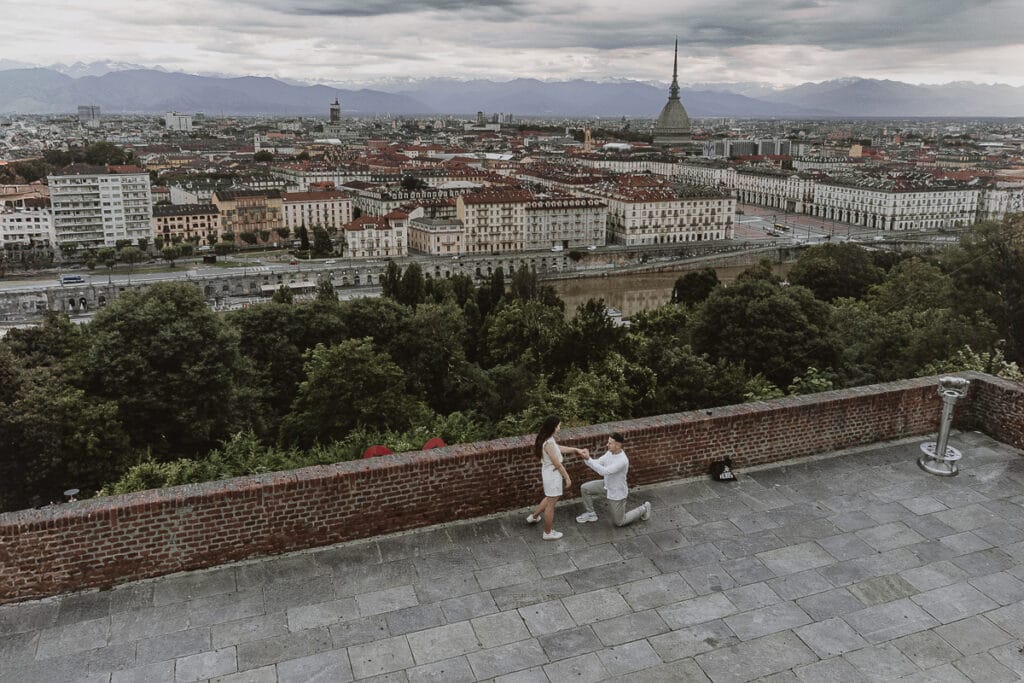 Proposta di matrimonio a Torino di Svajunaas ad Erika al Monte dei Cappuccini. Svajunaas si inginocchia davanti ad Erika.. Foto dal drone con il panorama su Torino