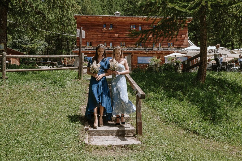 Destination wedding in Piemonte, elopement di Sophie e Angus a Sauze d'Oulx, Hotel Ciao Pais. le due damigelle camminano verso il luogo della cerimonia