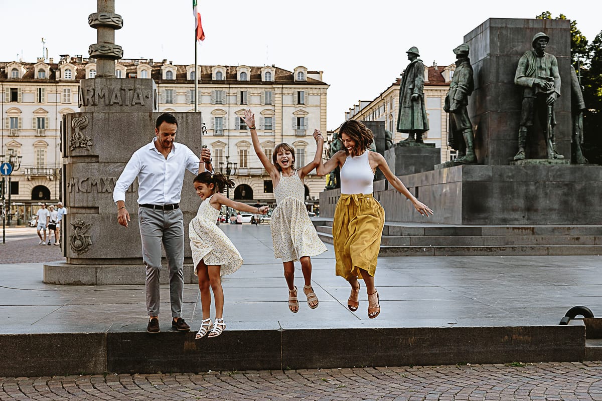 Fotografia di famiglia in vacanza a Torino: famiglia americana salta in piazza Castello davanti al monumento