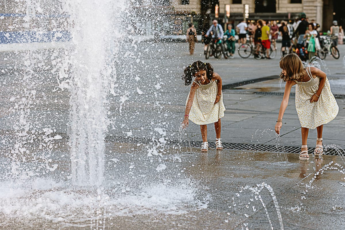 Fotografia di famiglia in vacanza a Torino: bambine giocano con l'acqua delle fontane di piazza Castello