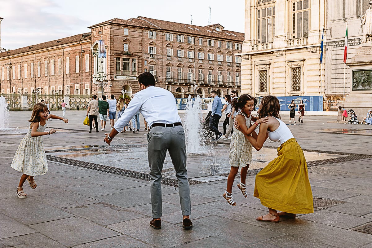 Fotografia di famiglia in vacanza a Torino: famiglia gioca in piazza Castello