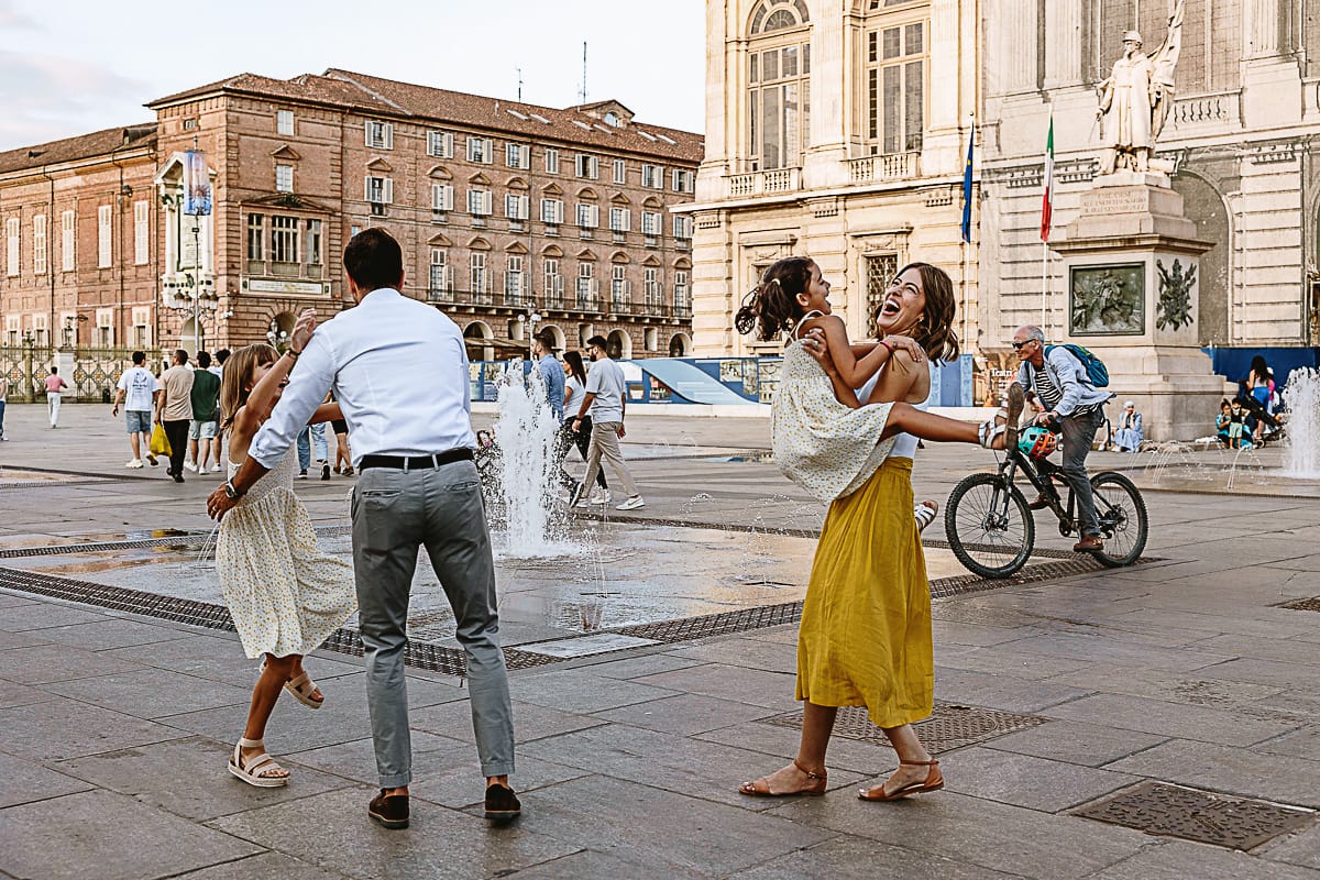Fotografia di famiglia in vacanza a Torino: famiglia gioca in piazza Castello