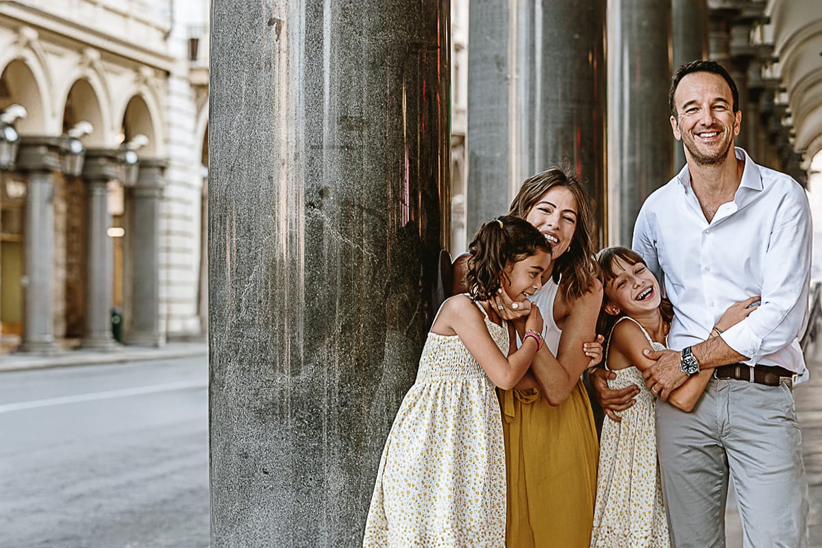 Fotografia di famiglia in vacanza a Torino: famiglia abbracciata sotto i portici di via Roma.
