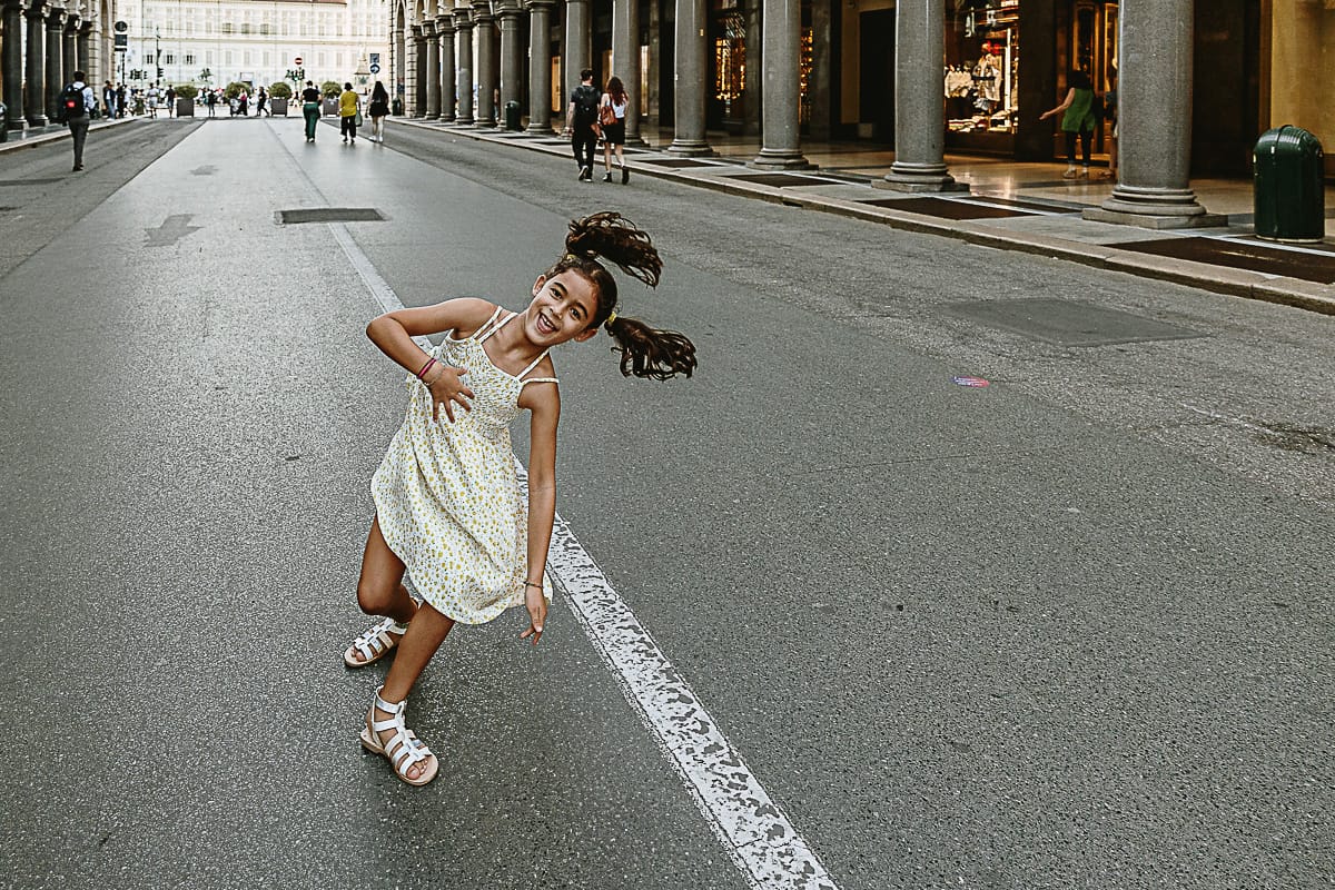 Fotografia di famiglia in vacanza a Torino: bambina fa la ruota in via Roma