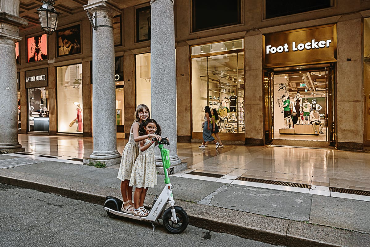 Fotografia di famiglia in vacanza a Torino: bambine su di un monopattino in via Roma