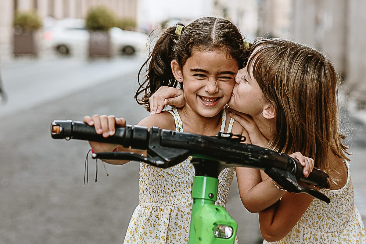 Fotografia di famiglia in vacanza a Torino: bambine su di un monopattino in via Roma