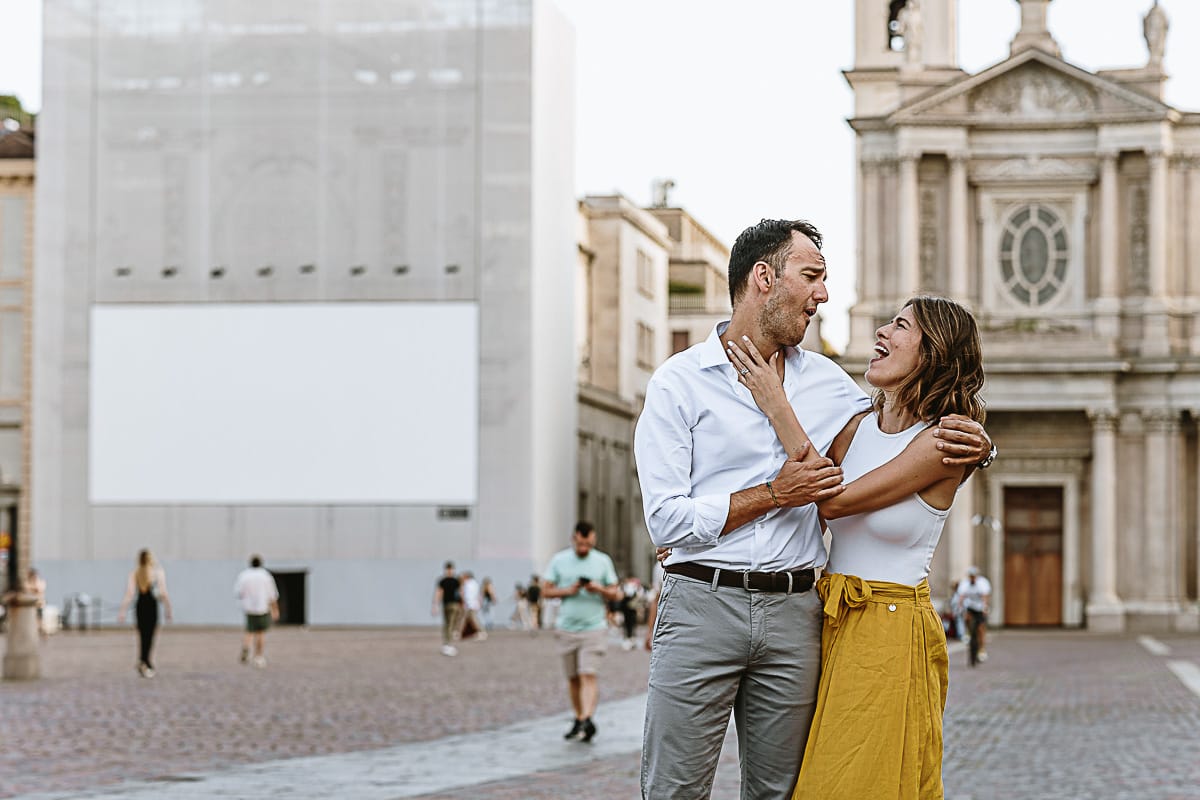 Fotografia di famiglia in vacanza a Torino: genitori si guardano e si accarezzano in piazza San Carlo.