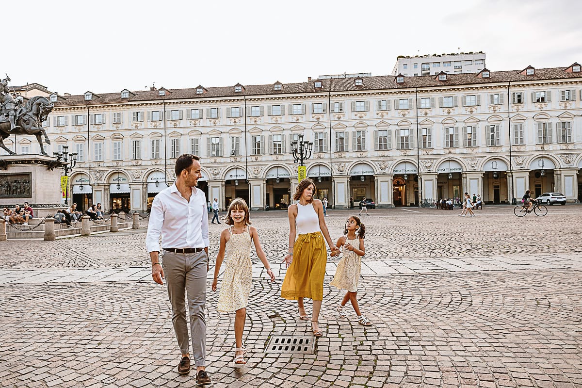 Fotografia di famiglia in vacanza a Torino: famiglia cammina in piazza san Carlo.