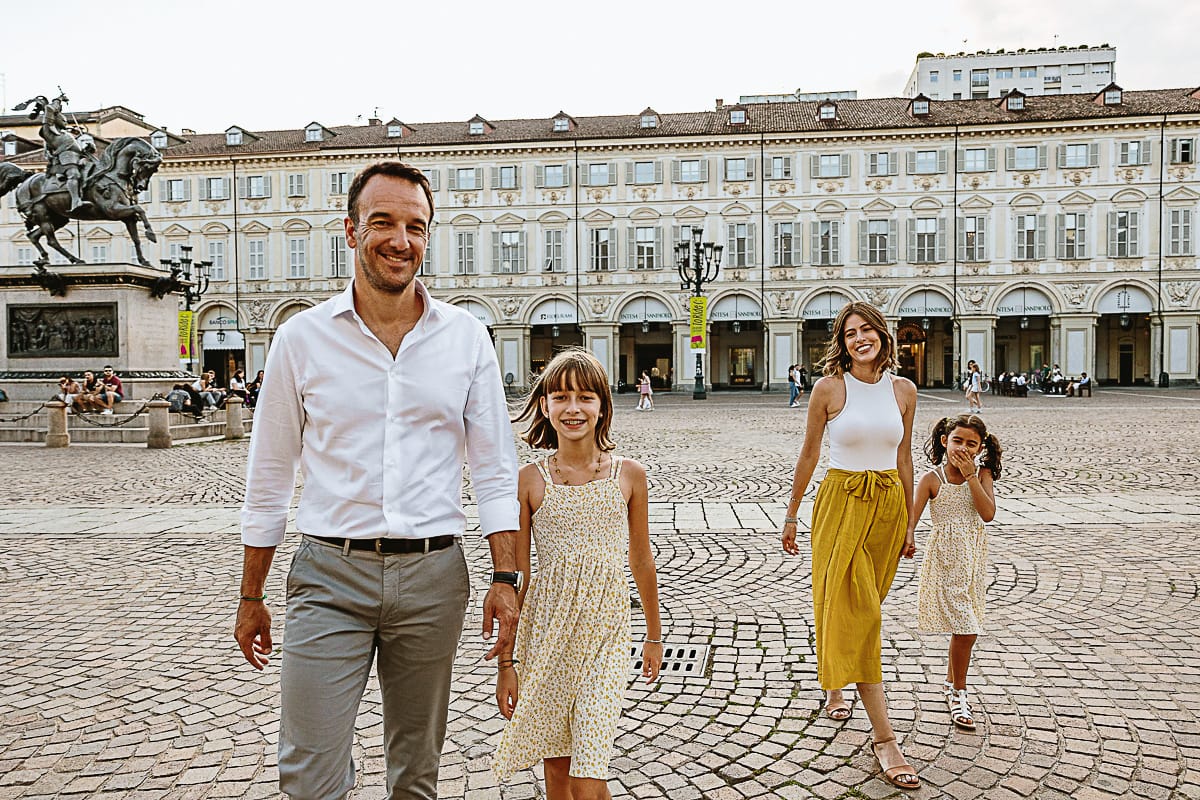 Fotografia di famiglia in vacanza a Torino: famiglia cammina in piazza San Carlo