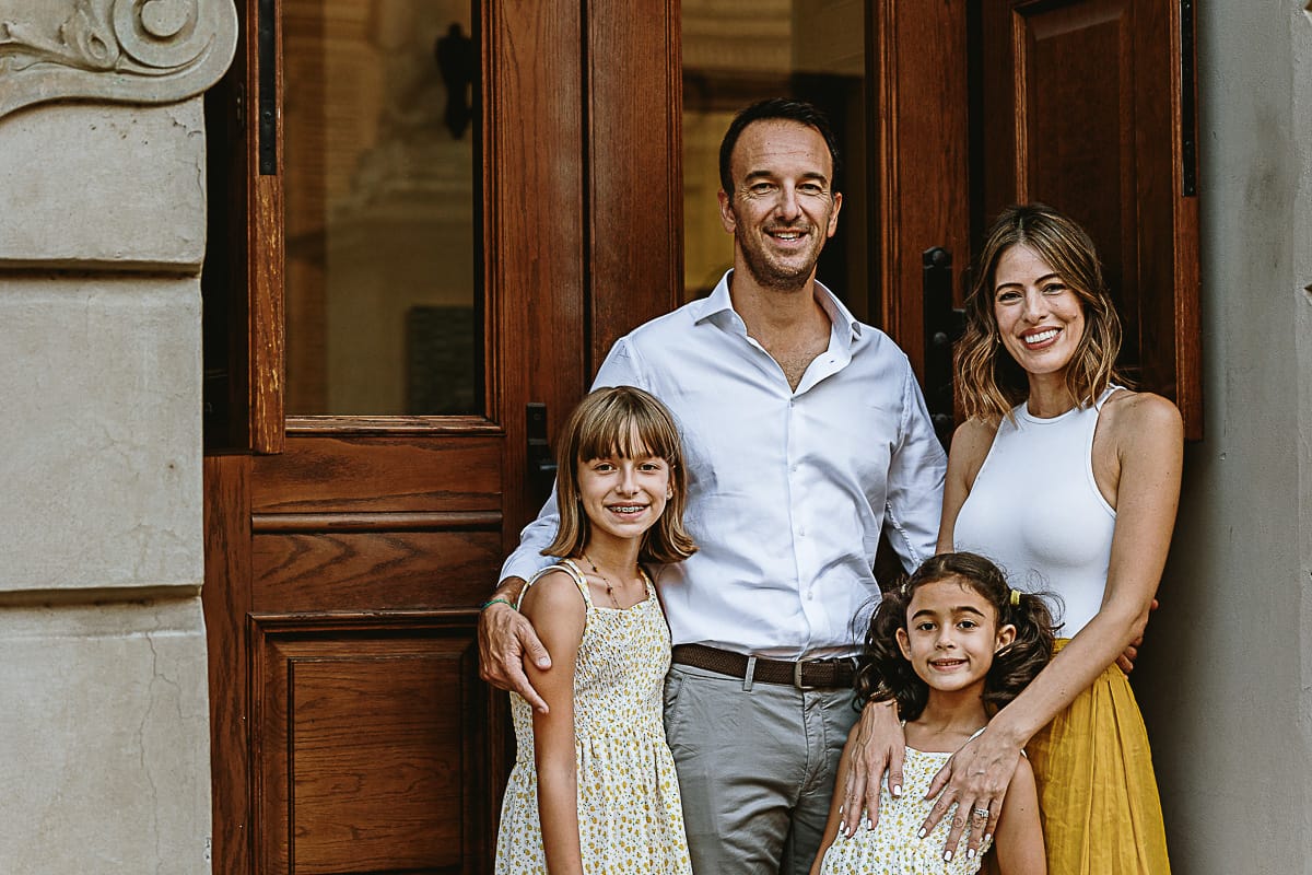 Fotografia di famiglia in vacanza a Torino: famiglia in piazza Carignano davanti al portone del Teatro Alfieri, con palazzo Carignano riflesso nei vetri dietro di loro.