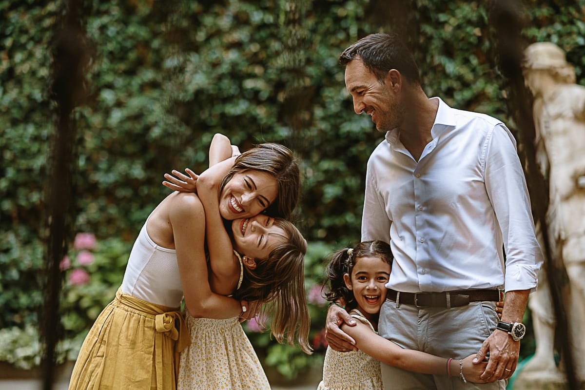 Fotografia di famiglia in vacanza a Torino: famiglia americana si abbraccia dietro un pozzo in un cortile di un palazzo del centro.