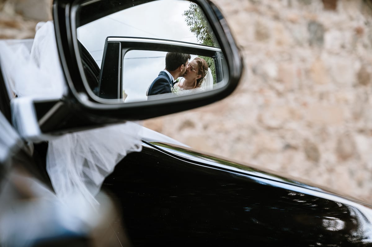 Matrimonio a Villa Ala di Rivalba (TO). Sposi si baciano riflessi nello specchietto laterale.