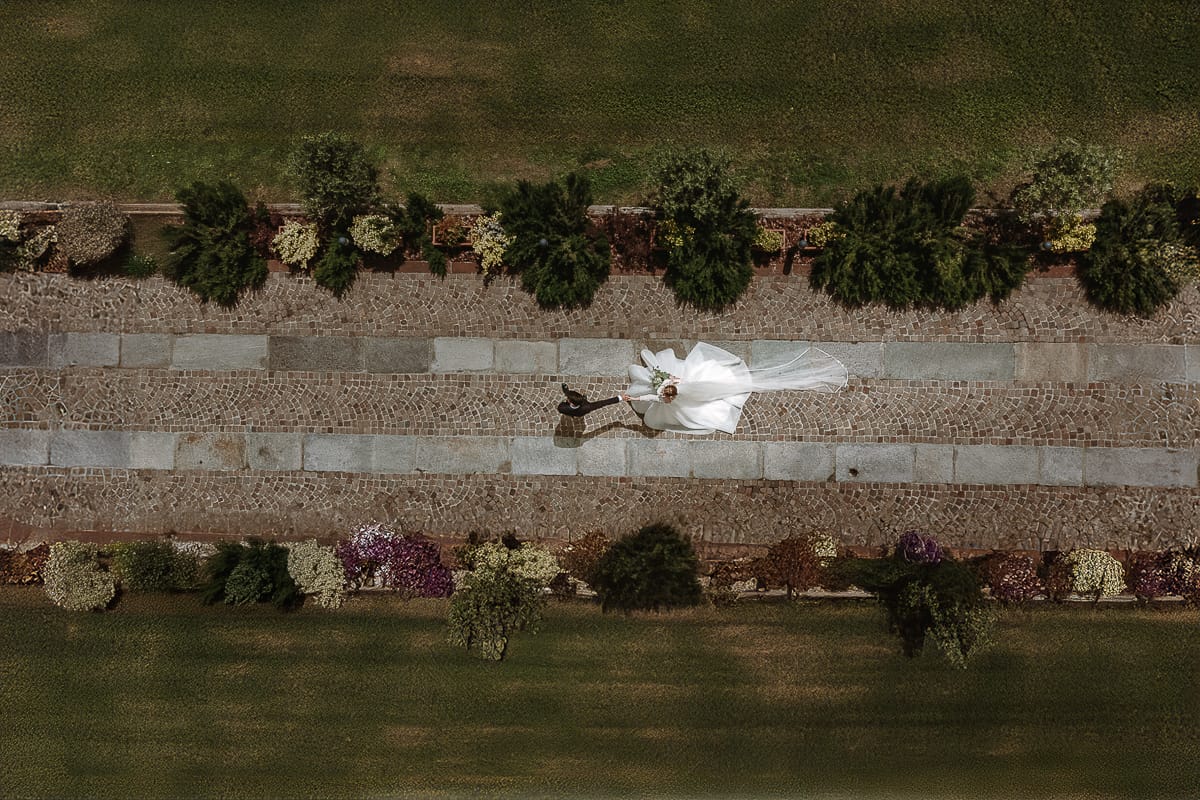 Matrimonio a Villa Ala di Rivalba (TO). Sposi camminano nel vialetto d'ingresso della villa. lo sposo tira la sposa. La foto è stata scattata dal drone.