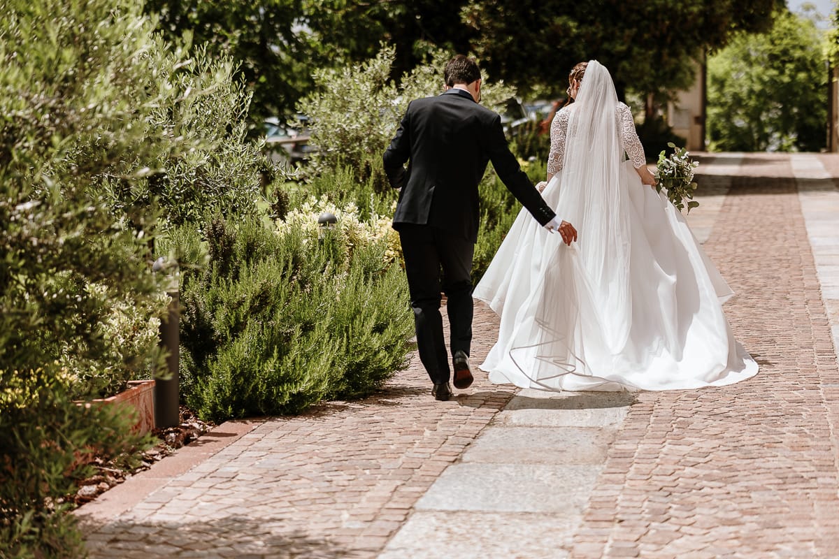 Fotografo matrimonio Torino. Sposi cammonano nel vialetto di Villa Ala. lo sposo sistema il vestito della sposa.