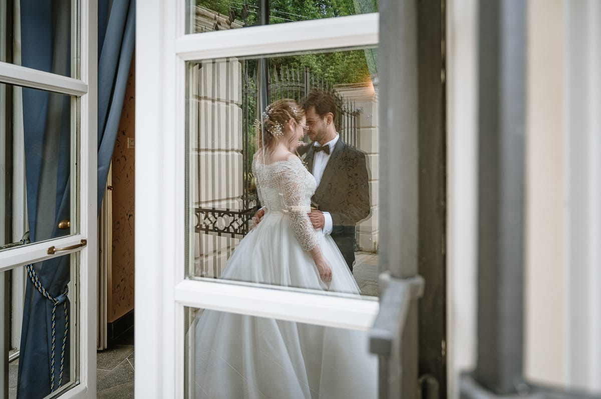 Fotografo matrimonio Torino. Sposi fronte fronte riflessi nel vetro di una porta finestra